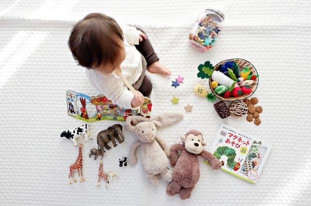Little toddler playing with colorful toy animals and storybook