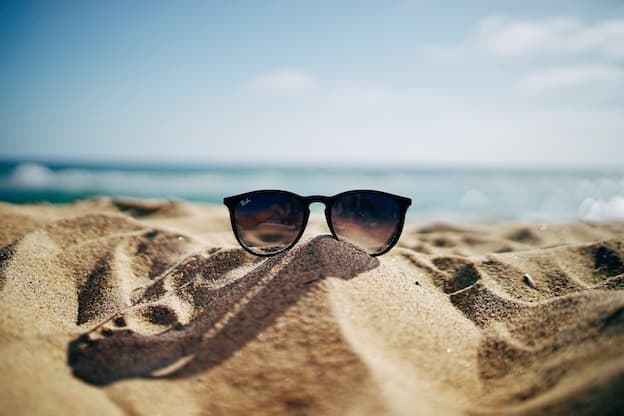 Classic sunglasses resting on warm golden sand dune