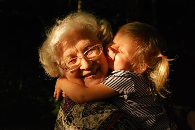Grandmother and granddaughter joyful hug in golden sunset