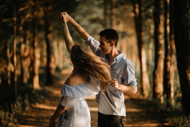Romantic couple dancing joyfully in pine forest path
