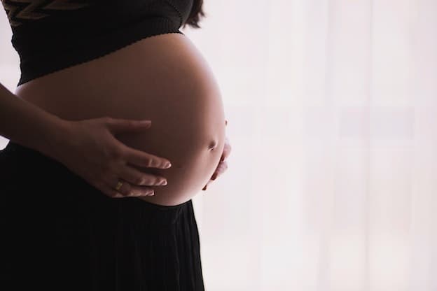 Gentle hands cradling expectant mother's baby bump