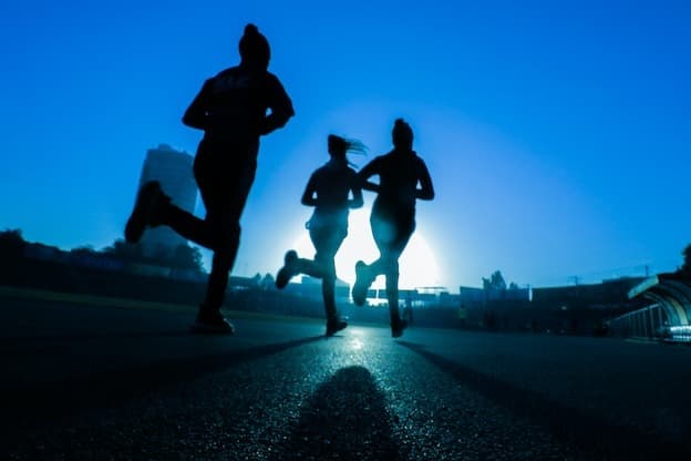 Athletic runners silhouette against golden morning sun