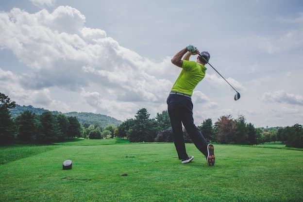 Golfer finishing powerful swing on fairway green